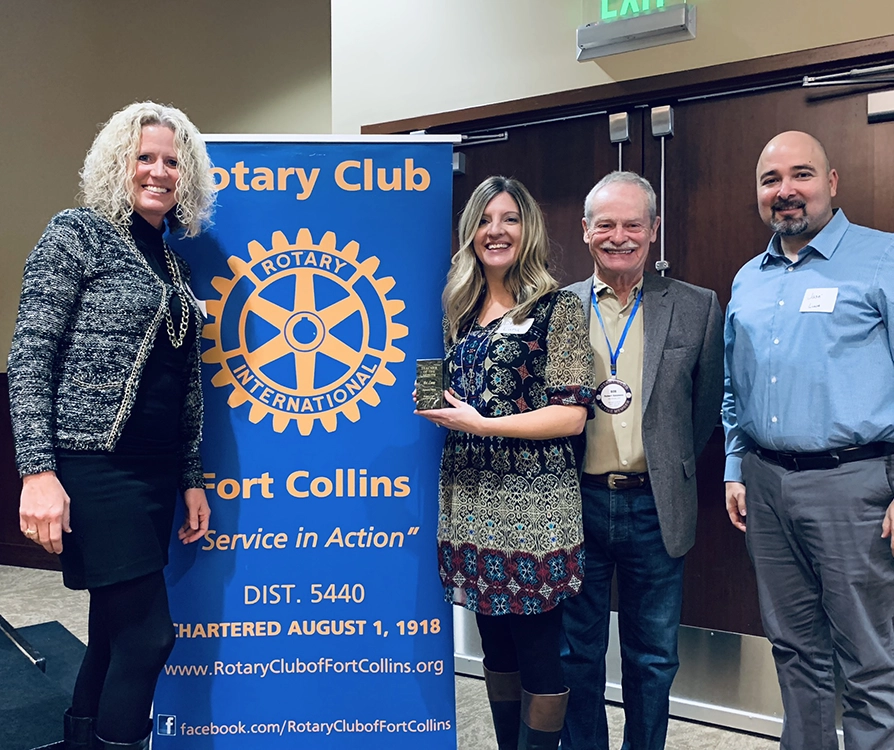 group of people smiling by rotary club sign