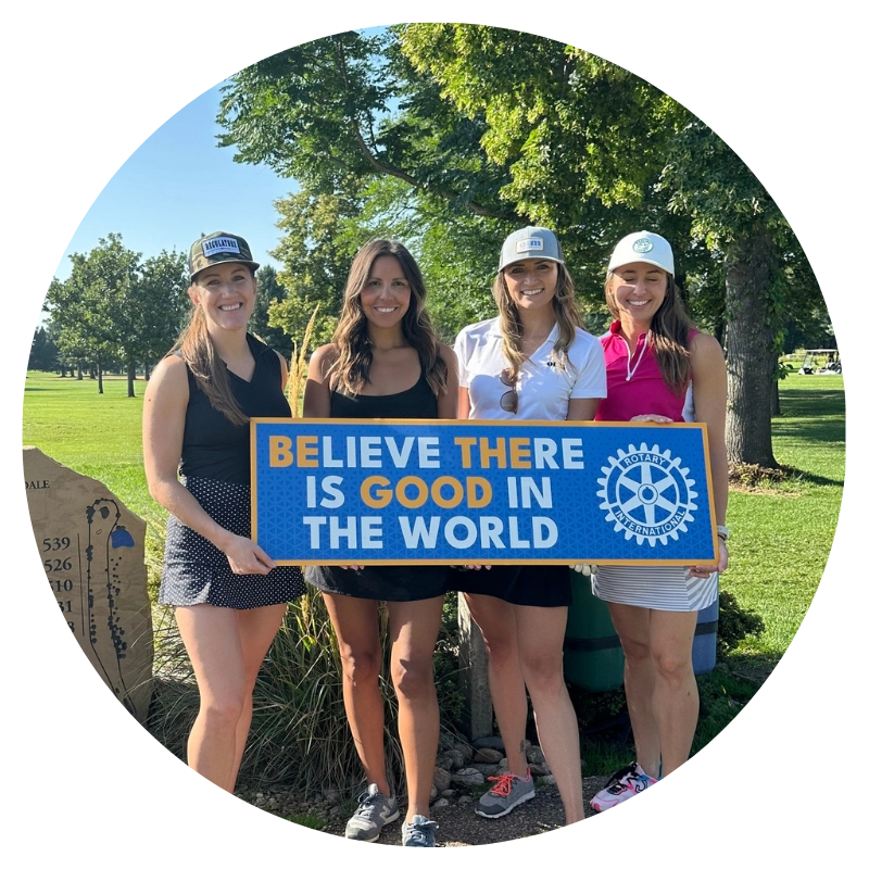 group of people at a golf course smiling and holding a sign